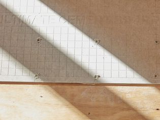 Cement backer board on wooden floor with light and shadows casted across