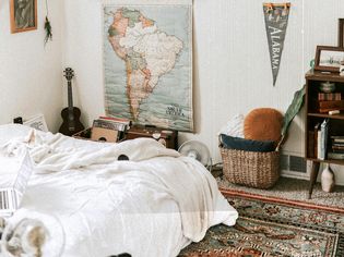 Cozy dorm room with white bedding and patterned rug. 