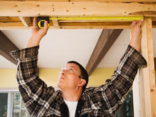 Workman measuring the length of a support beam