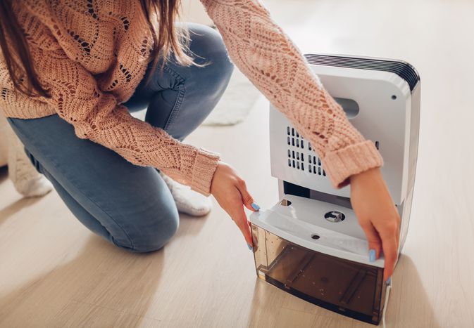 Woman emptying the water container of a dehumidifier