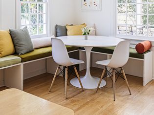 White Saarinen table with two chairs and window corner with benches