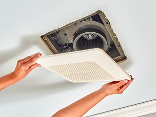 Bathroom exhaust fan installed in ceiling with white cover placed over