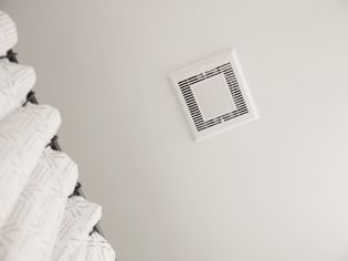 Bathroom exhaust fan in ceiling above shower curtain