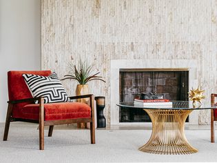 Midcentury modern coffee table with glass and rust-colored velvet chair in front of fireplace 