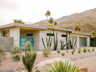 Midcentury modern home with rock garden and bright blue front door