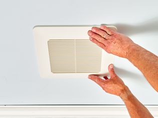 Exhaust fan cover being attached to ceiling with two hands