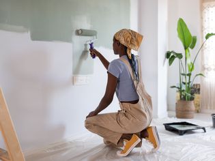 Woman painting a wall sage green