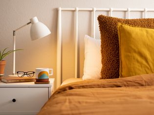 White table lap shining warm light on nightstand and bed with brown linens