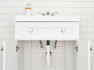 Bathroom sink doors open showing plumbing